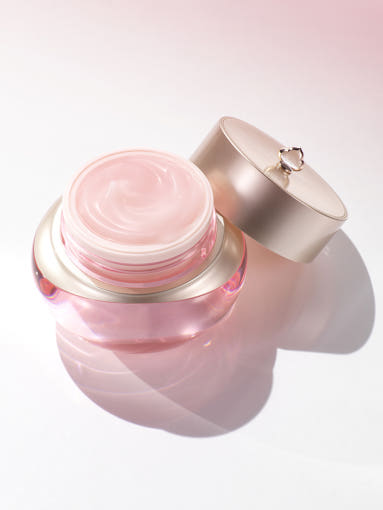 Pink cosmetic jar with a gold lid on a light pink background