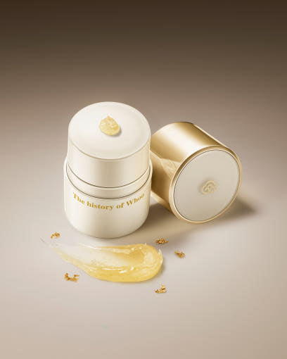 Two skincare containers with a gold droplet on a beige background