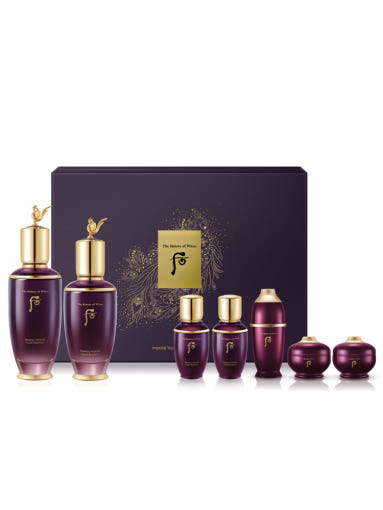 Set of purple skincare products with gold accents in front of a branded box on a white background